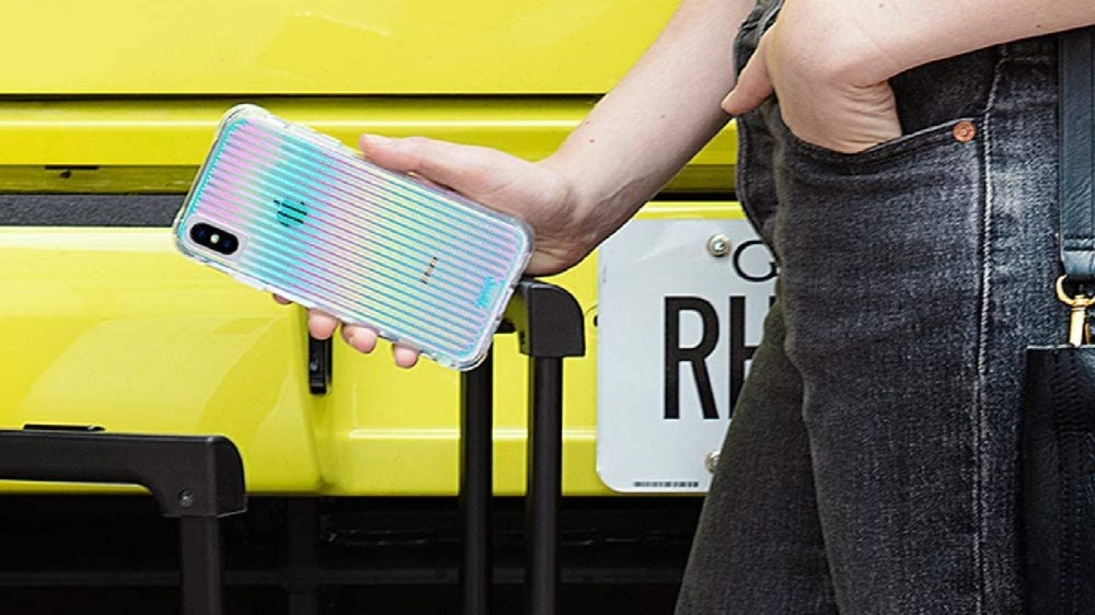 A woman holds her iPhone in its shiny and colorful case.