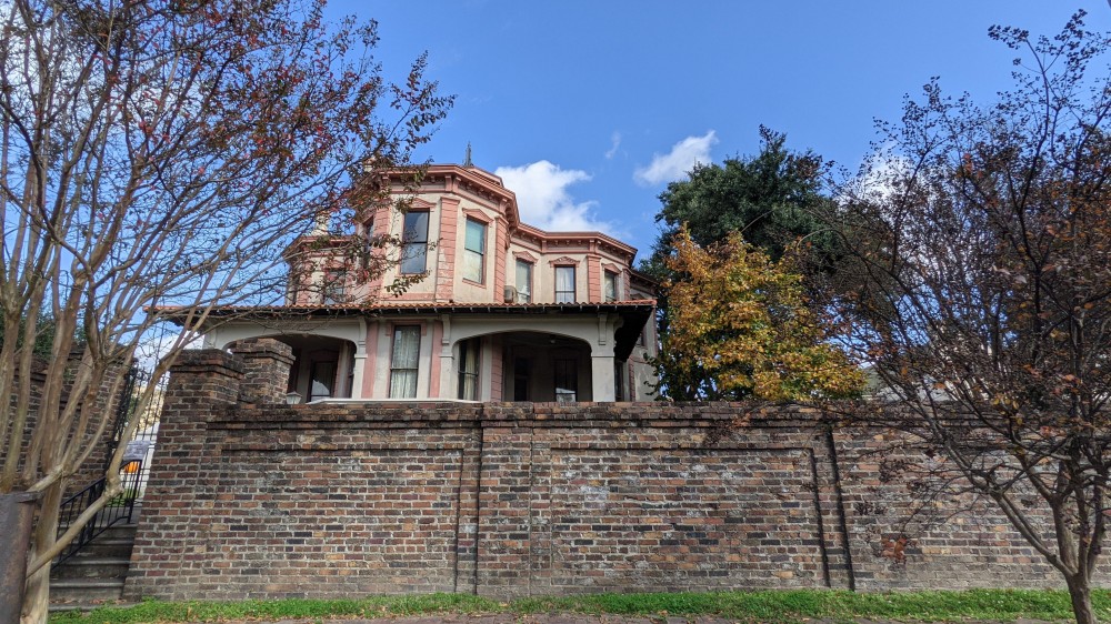 A photo of a house and brick fence.