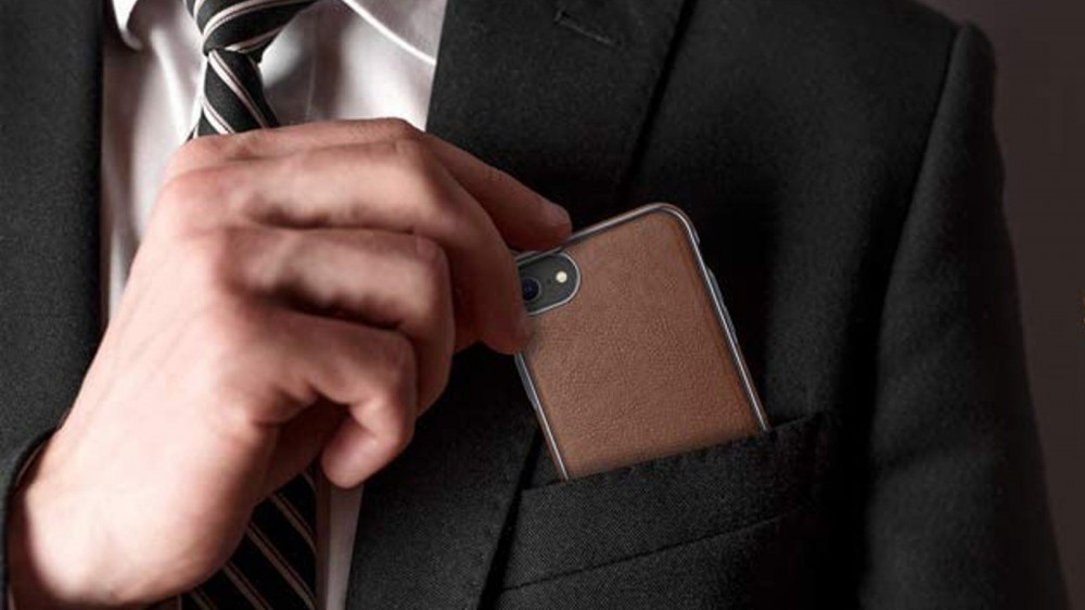 A man places an iPhone SE in his suit coat breast pocket.